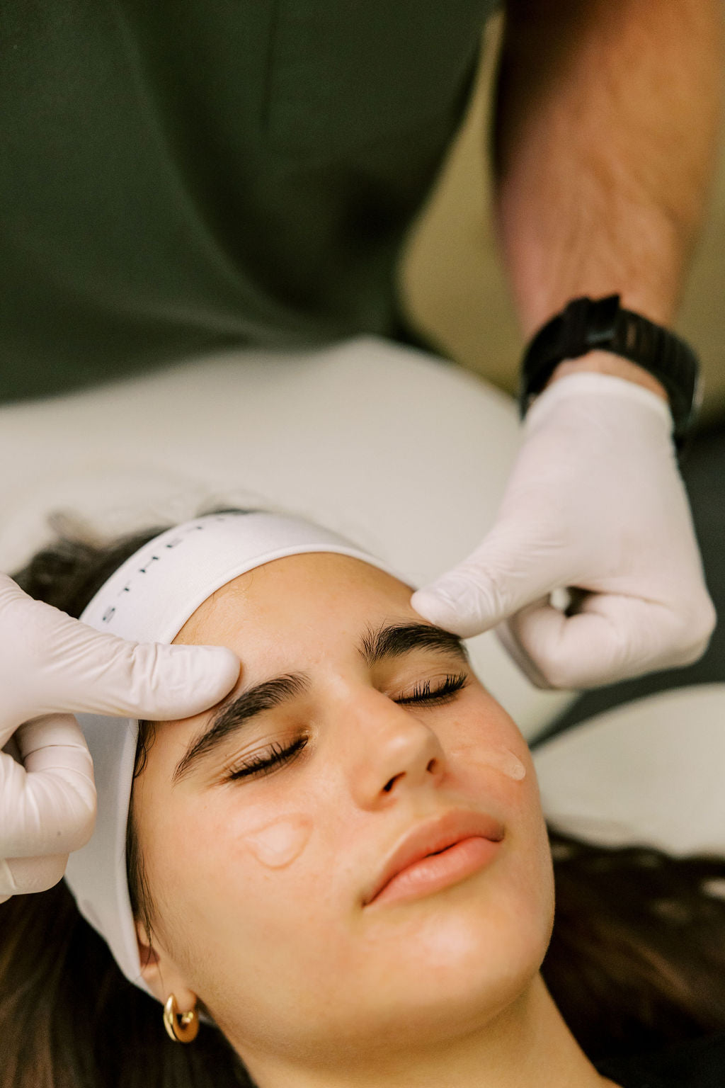 Person receiving a facial treatment with a professional wearing gloves in Asheville, NC